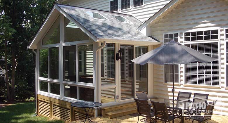 White four season sunroom with vinyl frame, glass knee walls, glass roof panels and shingled gable roof.