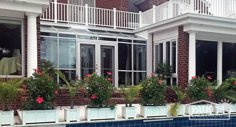 White solarium with single-slope roof enclosing an existing covered porch.