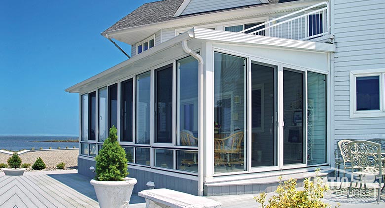 Elite three season sunroom with glass knee wall and single-slope roof.