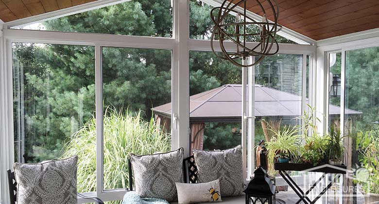 Elite three season sunroom with white aluminum frame, gable roof and custom wood ceiling.