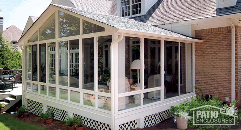 White elite three season room with glass knee walls and shingled gable roof.