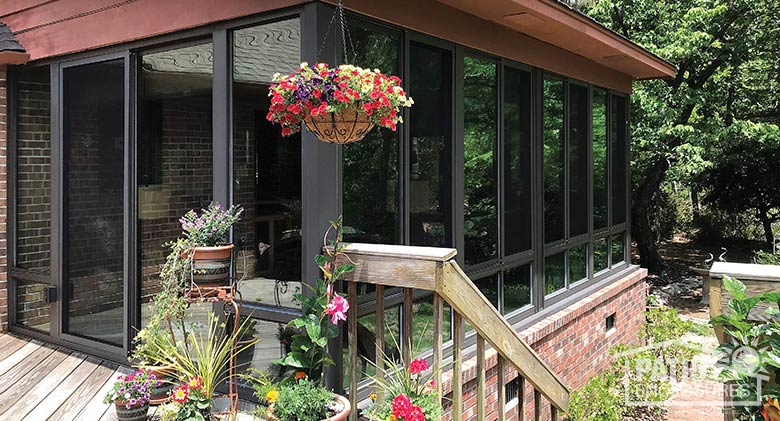 Bronze three season sunroom with insulated glass enclosing an existing covered porch.