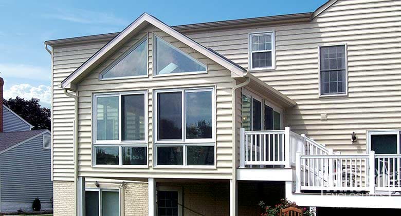 Traditional sunroom with white vinyl frame and glass knee wall with attached deck.