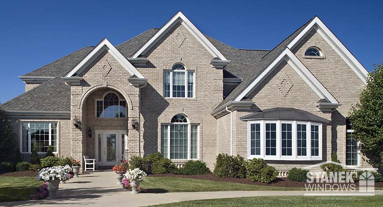 Five-lite bow window in white with colonial grids and shingled hip roof add character to the exterior of any home.