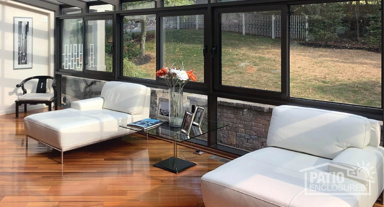 Interior image of a sunlit patio enclosure furnished with matching white chaise lounge chairs.