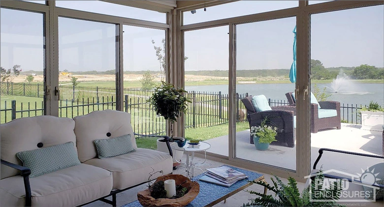 Beautiful interior of a patio enclosure looking out to outdoor patio with comfortable furniture and large pond and fountain.