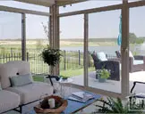 With a view of the lake, a beautiful sunroom is furnished with comfortable beige and blue furniture.