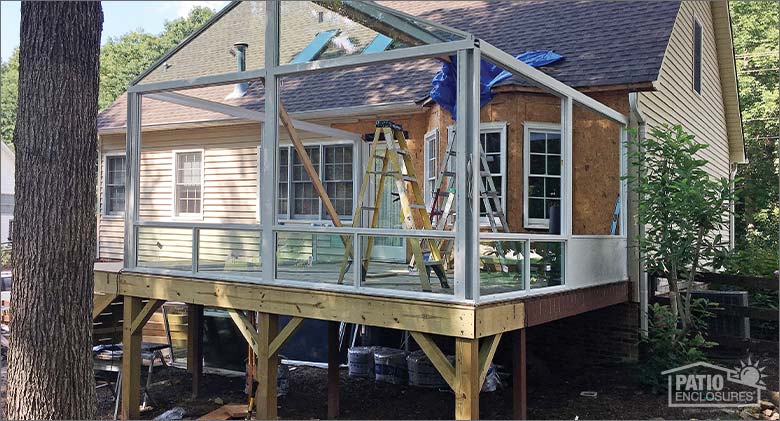 A gable-roofed sunroom in the process of being built showing a newly constructed deck foundation beneath it.