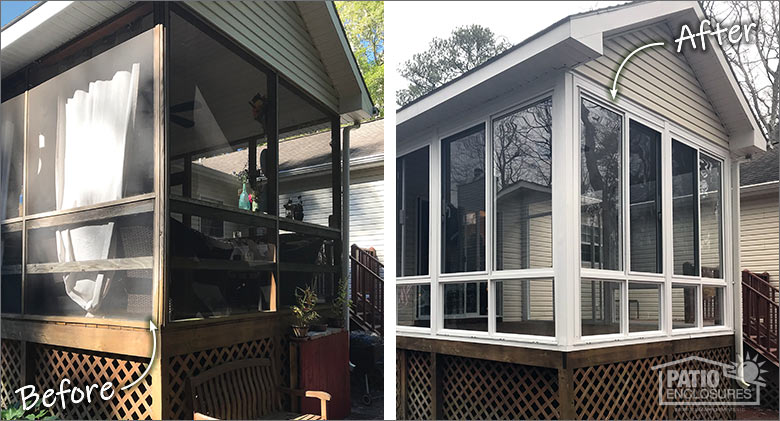 A tan house with a matching glass three-season porch with a gable roof, surrounded by neat landscaping.