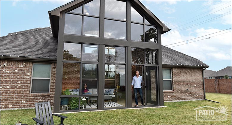 A man and a woman enjoing a three-season sunroom with soaring ceiling on a one-story brick home.