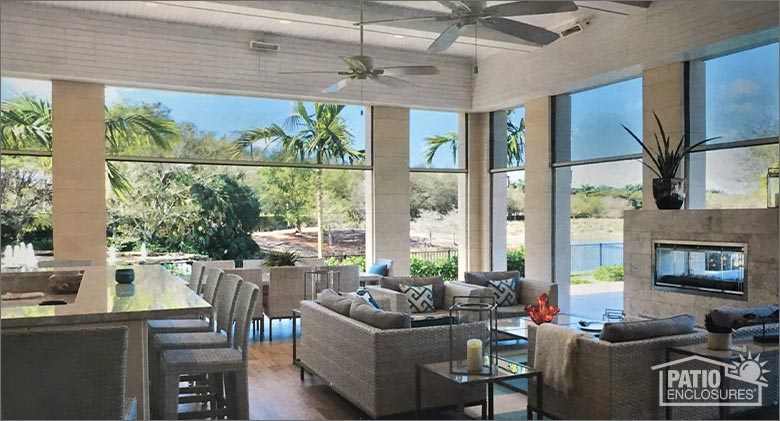 The interior of a covered patio with dining and seating areas and retractable screens partly closed.