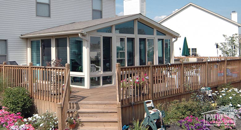 Sandstone four season sunroom with vinyl frame, glass knee walls and shingled, gable roof.