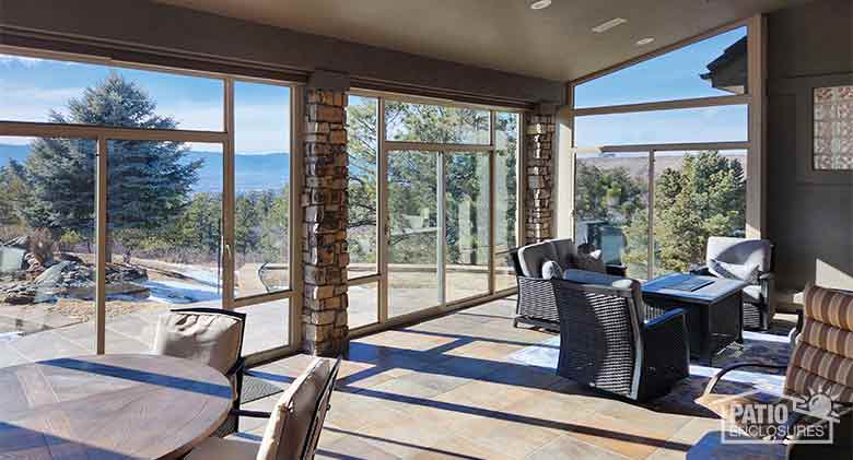 A sunroom enclosure with tan frame between stone columns provides abundant natural light and fabulous views.
