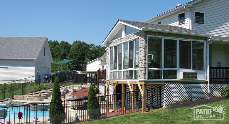 White four-season sunroom with aluminum frame, glass knee walls, gable roof and stone fascia.
