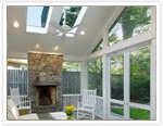 Embedded ceiling lighting, multiple skylights, wall-to-wall glass, and a gorgeous fireplace provide a tribute to light in this sunroom.