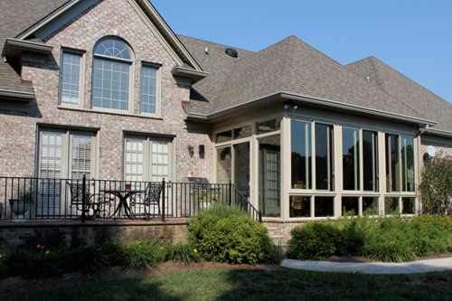 Outside View of a Sunroom Under Existing Roof Attached to a Brick House