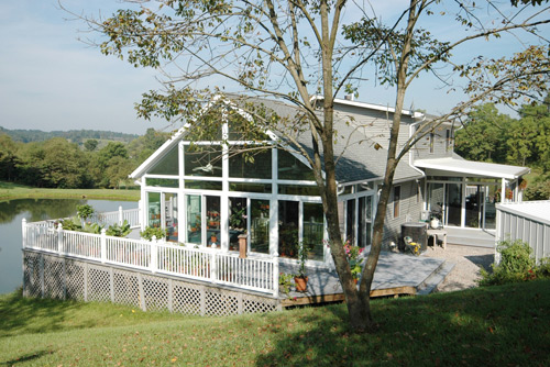 Outside View Of A Sunroom With Vaulted Ceiling As Part Of A Deck Overlooking A Lake