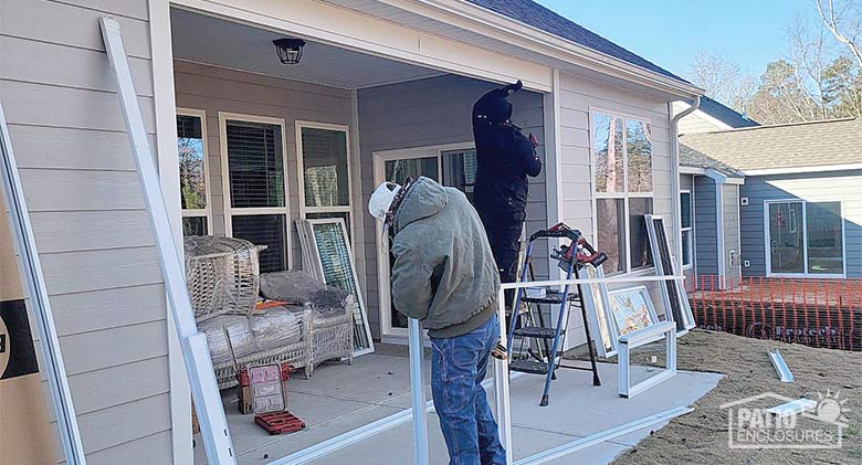 A patio on the back of a house being enclosed with glass. One can see parts of the room waiting to be installed.