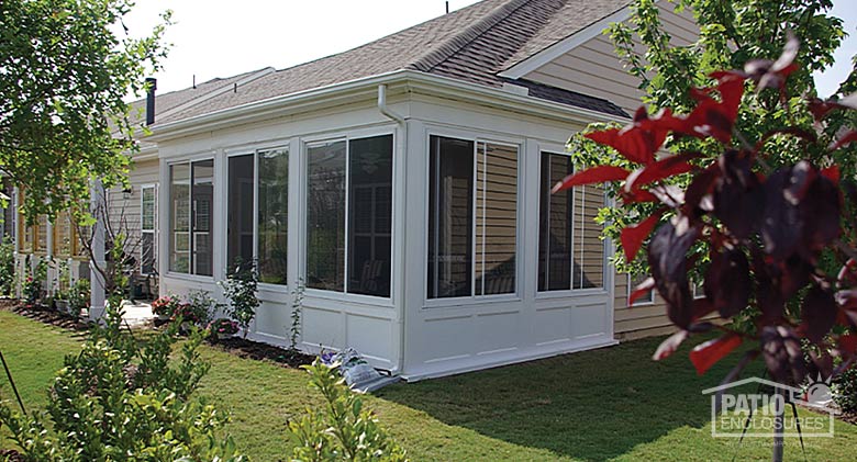 A white three-season room with sliding glass windows and solid knee wall on a beige home