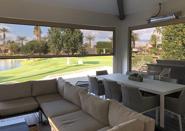 Seating and dining areas in a covered patio and shaded by retractable screens halfway down.
