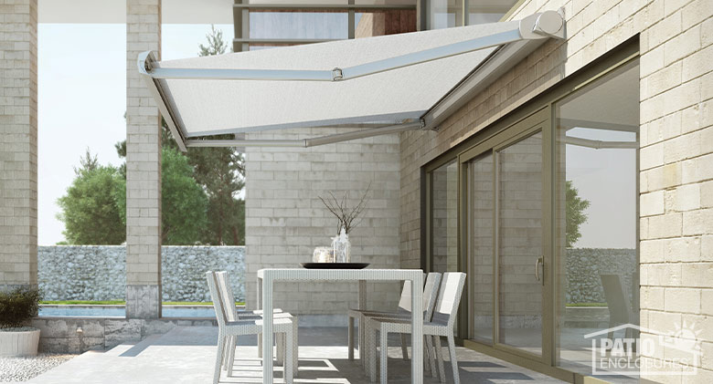 A white dining table and chairs on an outdoor patio shaded by a white retractable awning.