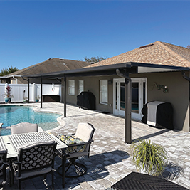 Three-season Elite glass patio enclosure with bronze frame and solid knee wall.